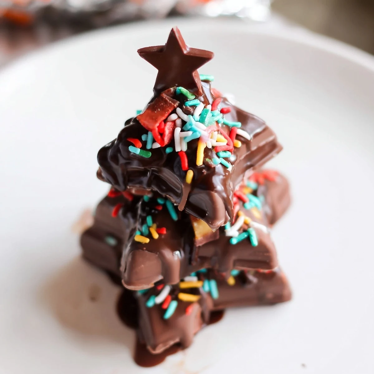 Melted chocolate drizzled over festive Kinder Christmas Trees, crowned with a star, ready to eat.