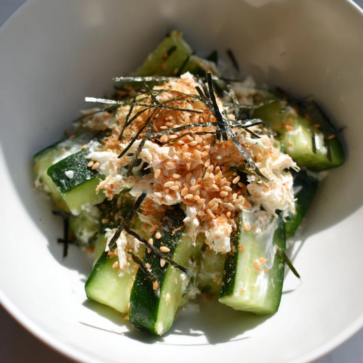 Fresh California Roll Cucumber Salad with shredded imitation crab, creamy mayo, and toasted sesame seeds on a platter.