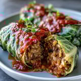 Savory plant-based cabbage rolls with lentils and brown rice, served beside crusty bread for dipping.  