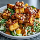 Golden fried tofu cubes rest atop a vibrant mix of mango, cabbage, and bell peppers, finished with chopped peanuts.  