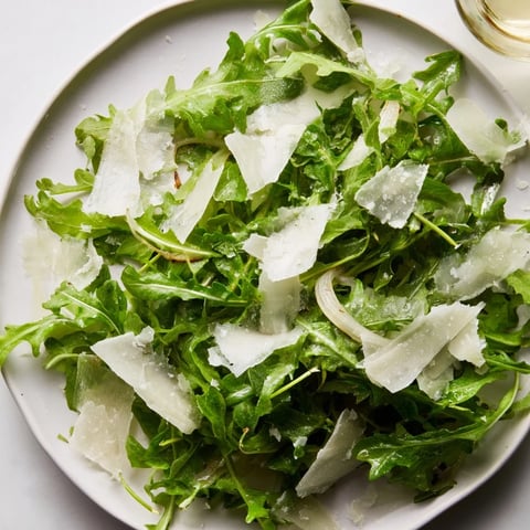 Vibrant arugula salad with lemon dressing, Parmesan shavings offer a refreshing, citrusy taste.