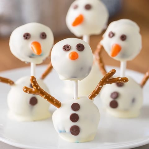 Sweet Oreo Snowman Cake Pops feature mini chocolate chip eyes and a cheerful orange nose.