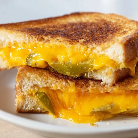 A warm, gooey Cheddar Jalapeño Grilled Cheese slice, revealing melted cheese and spicy peppers.