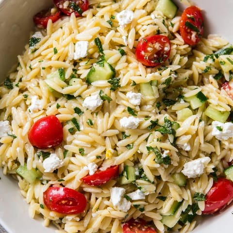 Fork-ready Greek Orzo Salad tossed with parsley, red onion, and zesty lemon-oregano dressing, ideal for a refreshing lunch.  
