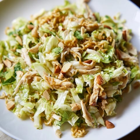 A close-up of Crunchy Ramen Chicken Salad with shredded cabbage, carrots, and toasted almonds in a sweet sesame dressing.  