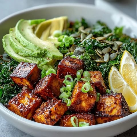 A close-up view of a Tofu Breakfast Bowl with avocado, kale, and lemon wedges, perfect for a nourishing vegan start.