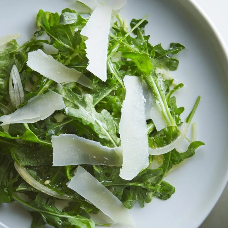 Arugula salad served, showcasing peppery greens coated in tangy lemon dressing, ready to enjoy.