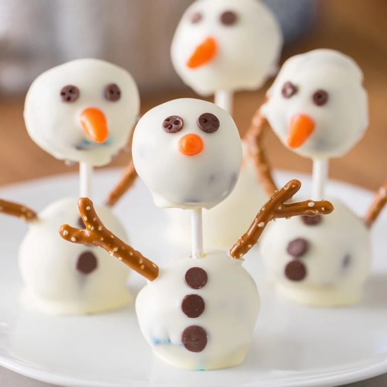 Sweet Oreo Snowman Cake Pops feature mini chocolate chip eyes and a cheerful orange nose.
