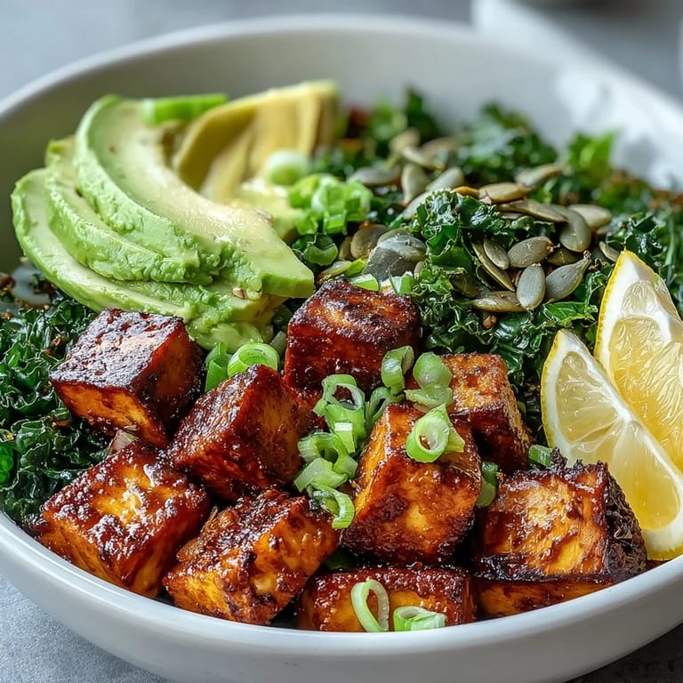 A close-up view of a Tofu Breakfast Bowl with avocado, kale, and lemon wedges, perfect for a nourishing vegan start.